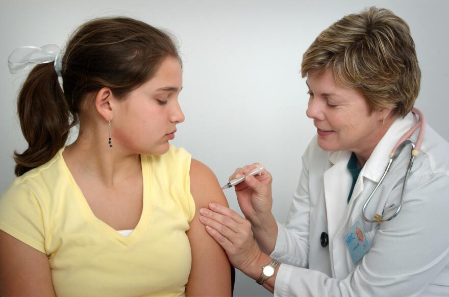 Image of nurse injecting vaccine in girl's arm. 