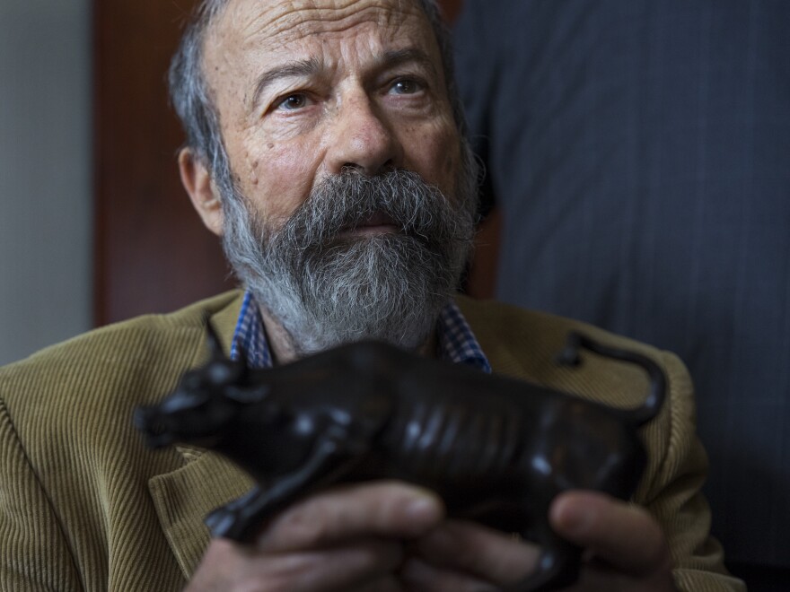 Arturo Di Modica holds a model of his <em>Charging Bull</em> during a news conference Wednesday.