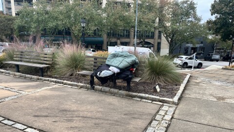 A sleeping bag and other belongings sitting on a bench outside of City Hall in downtown Athens.
