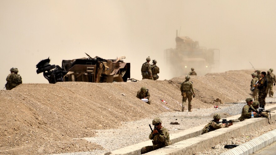 U.S. soldiers keep watch near the wreckage of their vehicle at the site of a Taliban suicide attack in Kandahar in August 2017.