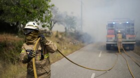 A firefighter pulls a hose while putting out a fire.