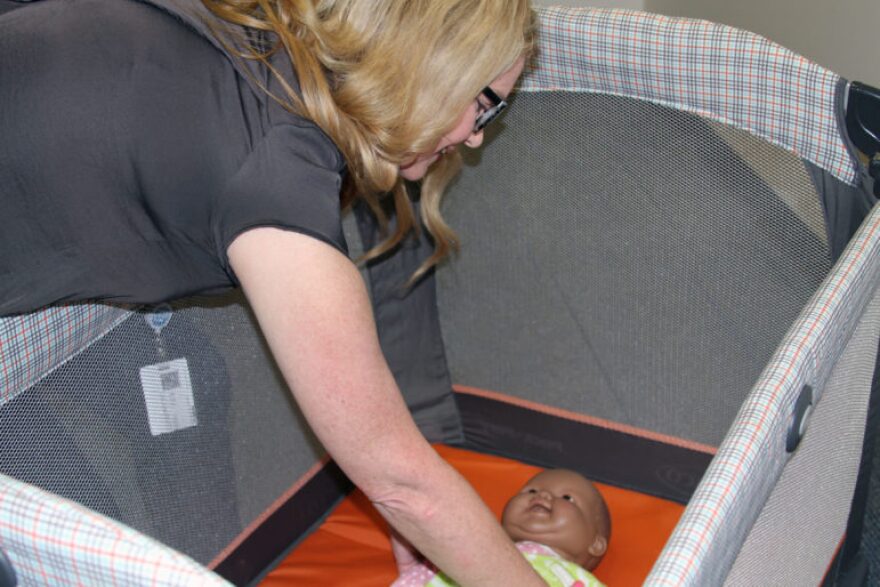 Taffy Henderson, a maternal and child health promotion specialist with the Oklahoma City-County Health Department, puts a doll into a crib that is meant to show what a safe-sleeping environment looks like. Henderson uses the crib to demonstrate safe-sleep