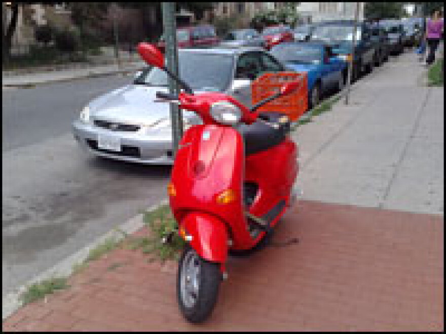 <strong>All Locked Up:</strong> This Vespa is on the sidewalk, away from road trouble. A solid chain helps deter thieves, though it should be secured to something more substantial than a traffic sign.