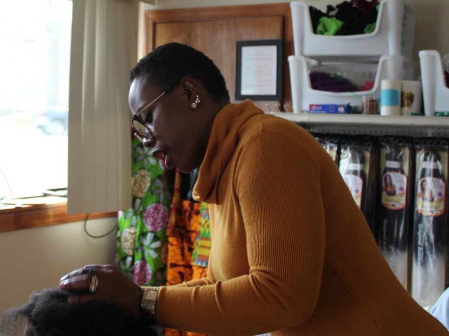 Angela Okafor styles the hair of a local mother inside her shop in Bangor, Maine. She opened her international food store and hair salon to provide needed services to Bangor's immigrant community.