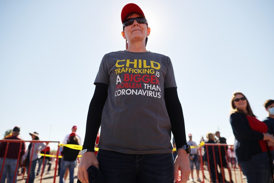 A woman wears a shirt promoting a QAnon conspiracy theory while waiting in line to attend a campaign rally with then-President Donald Trump on Oct. 28, 2020, in Goodyear, Arizona.