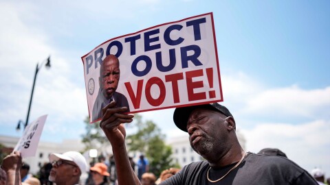 Aaron McGuire sings a spirtual song and holds a sign reading "Protect our vote" during a voting rally, Saturday, May 16, 2026, in Montgomery, Alabama.