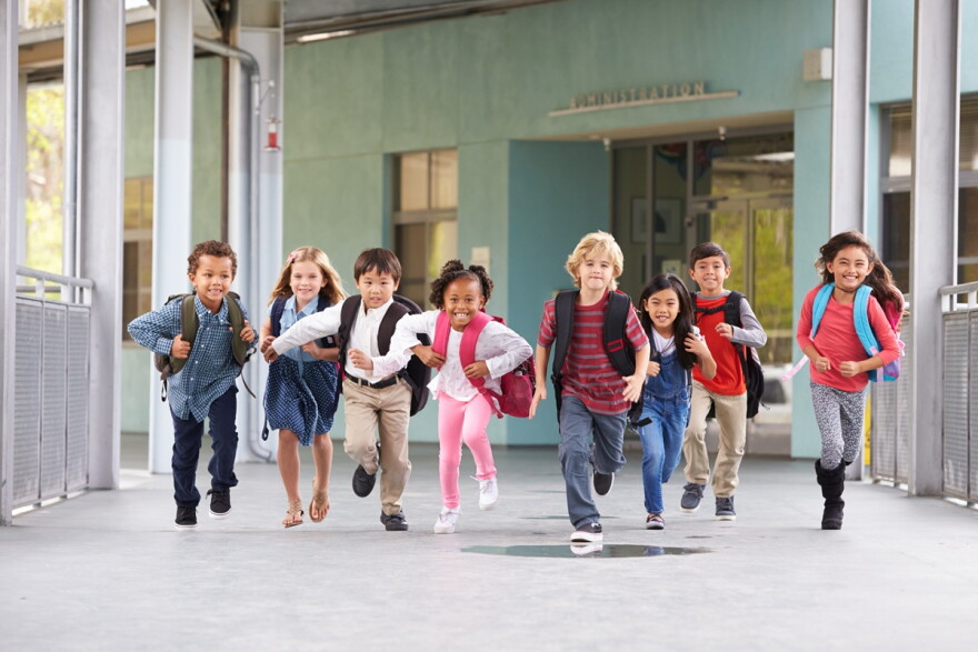 Group of elementary school kids running in a school corridor. 
