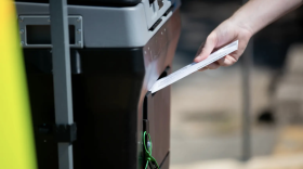 A voter drops off a ballot at the AG˰ټ County Tax Office, the only site where mail-in ballots can be hand delivered in the county.