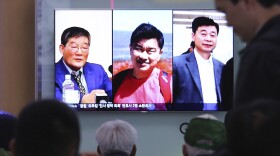 People watch a TV news report in Seoul, South Korea, on May 3, as the screen shows portraits of three Americans detained in North Korea: Kim Dong Chul (left) Tony Kim and Kim Hak-song (right). Three American prisoners in North Korea were released into U.S. custody on Wednesday, according to President Trump.