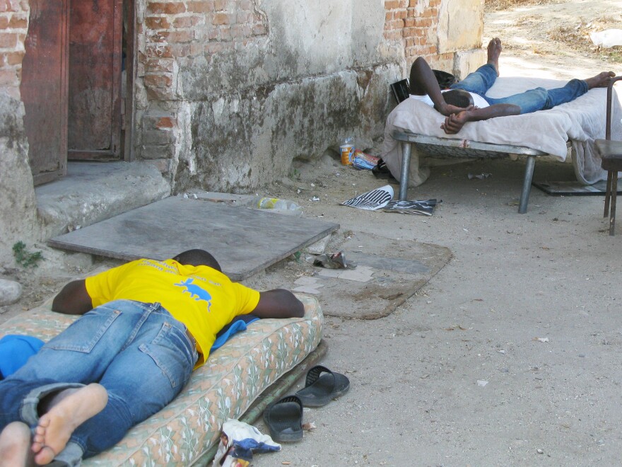 Men on cots wait for farm work near Calabria. Poor living conditions for migrant workers, sometimes without running water or toilet facilities, has led the Italian government to set up tents for them.