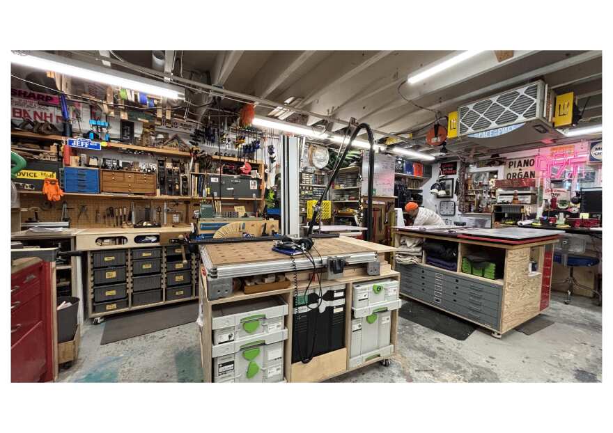 Inside Signs by Meng's studio. Jeffrey bends down to grab something. 