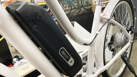an electric motor sits along the frame of a white bicycle