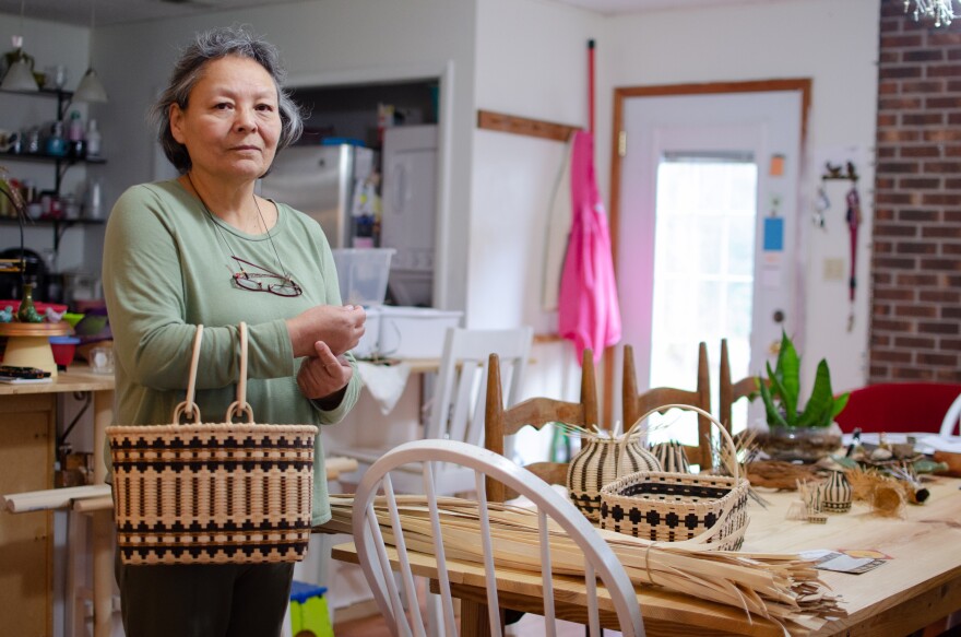 Betty Maney stands by her kitchen table, holding a handle basket. 