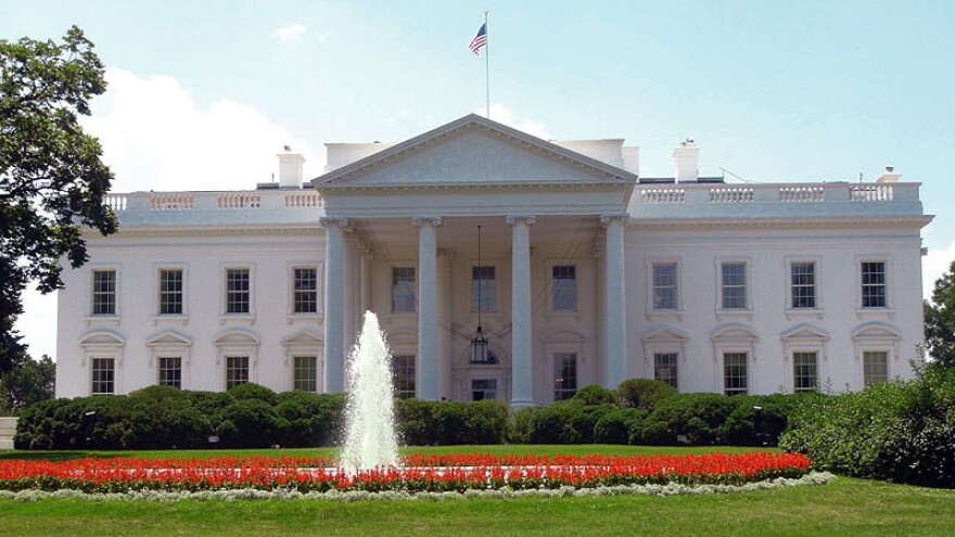  This is an image of the White House  featuring a circle of red flowers around a fountain in front