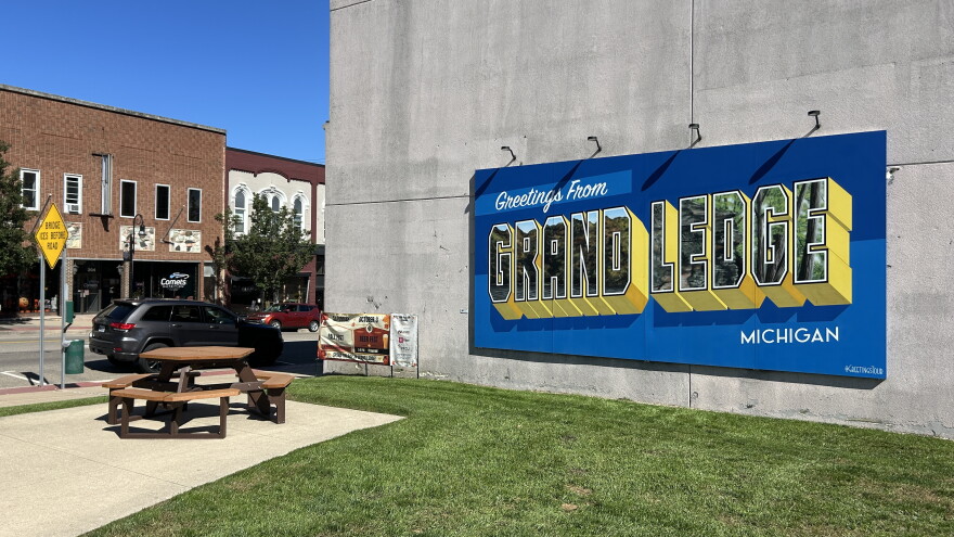 A large blue sign reads "Greetings from Grand Ledge, Michigan"