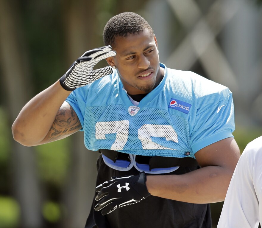 Carolina Panthers' Greg Hardy waves to fans as he arrives for an NFL football practice in Charlotte, N.C., Sept. 11, 2014.