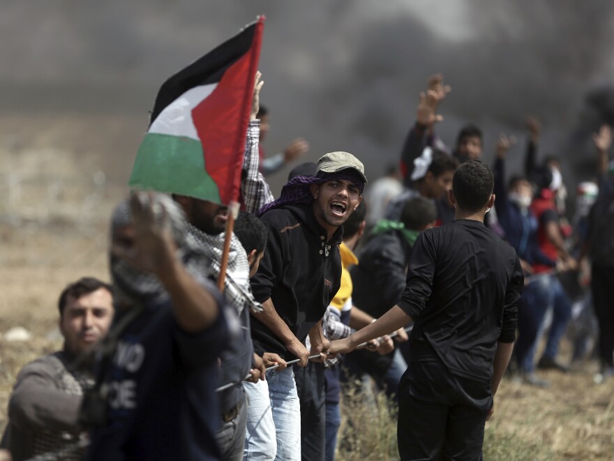 Palestinian protesters pull at part of a fence placed by the Israeli army during the demonstration Friday.