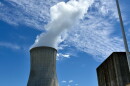 A wide shot of the Callaway Nuclear Power Plant cooling tower. It's wider at the top and bottom and white water vapor comes from the top. The sky is light blue with some slim clouds. 