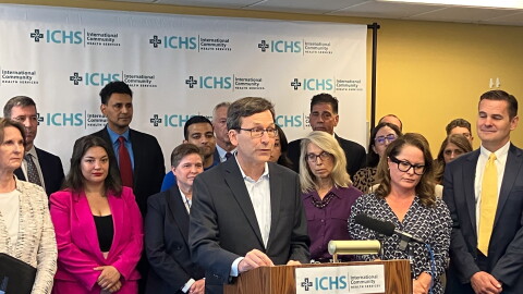 Gov. Bob Ferguson stands at a podium with a crowd behind him. 