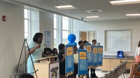 Baltimore City Schools CEO Sonja Santelises and students at Montebello holding signs for the new “soft skills” added to the plan. Photo by Bri Hatch/WYPR.