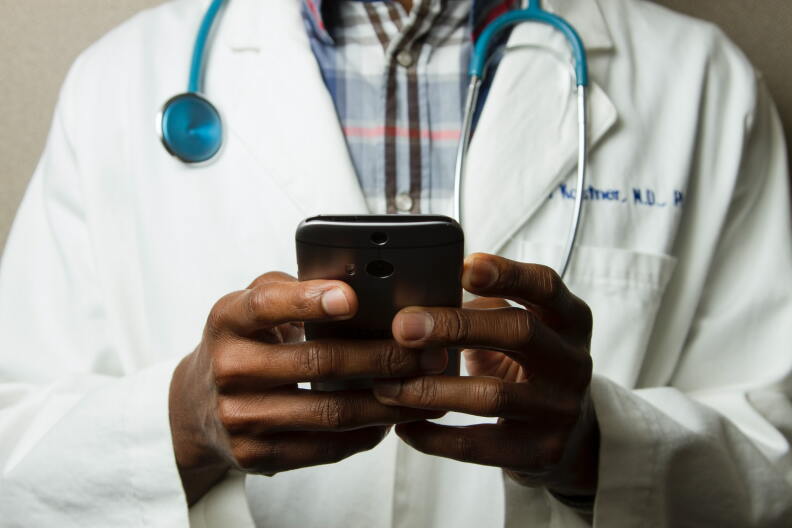 A doctor holds a cell phone.