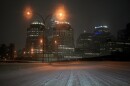 a snow covered road with a city skyline in the background, lit up at night