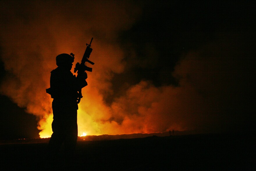 Sgt. Robert B. Brown with Regimental Combat Team 6 watches over the civilian firefighters at a burn pit in Fallujah, Iraq, on May 25, 2007. The appearance of U.S. Department of Defense (DoD) visual information does not imply or constitute DoD endorsement.