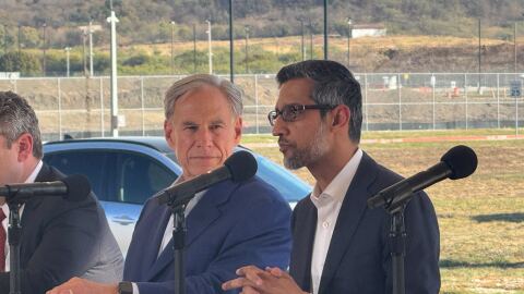 Two men sitting next to each other and speaking into microphones.