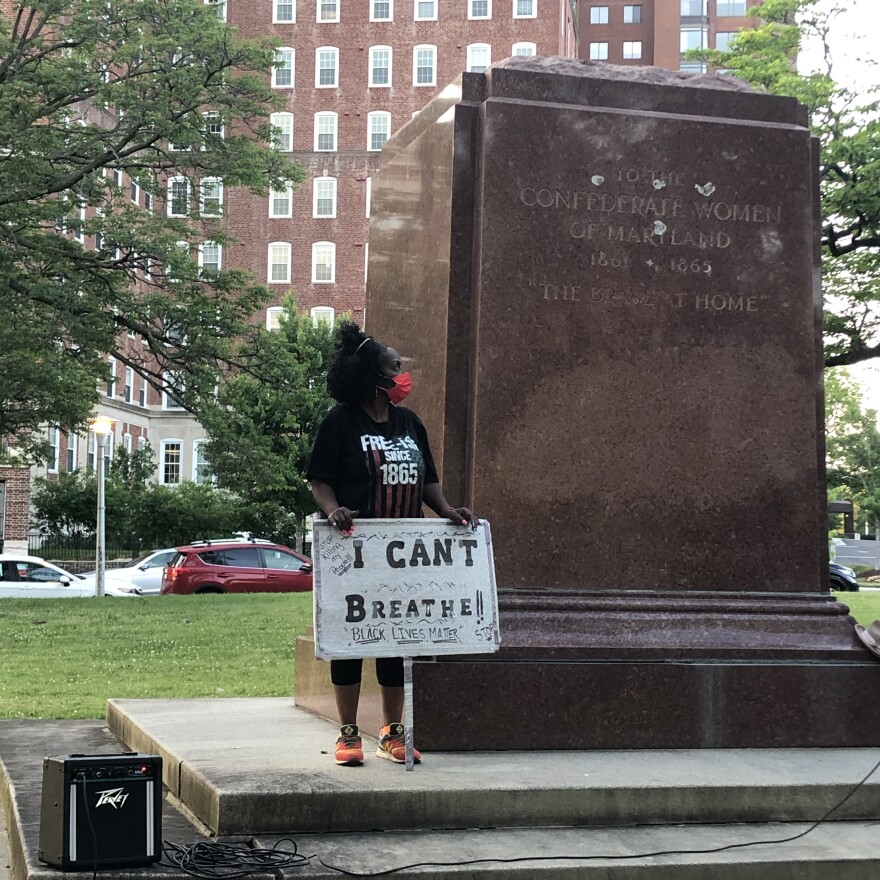 A woman at Tuesday's vigil, looking up at what was once the Confederate Women's Statue in Bishop Square Park. She wears a shirt that reads "FREE-ISH SINCE 1865."