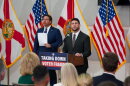 Two men in suit and ties by podium that reads "Taking Down Voter Fraud." A bunch of flags are behind them 
