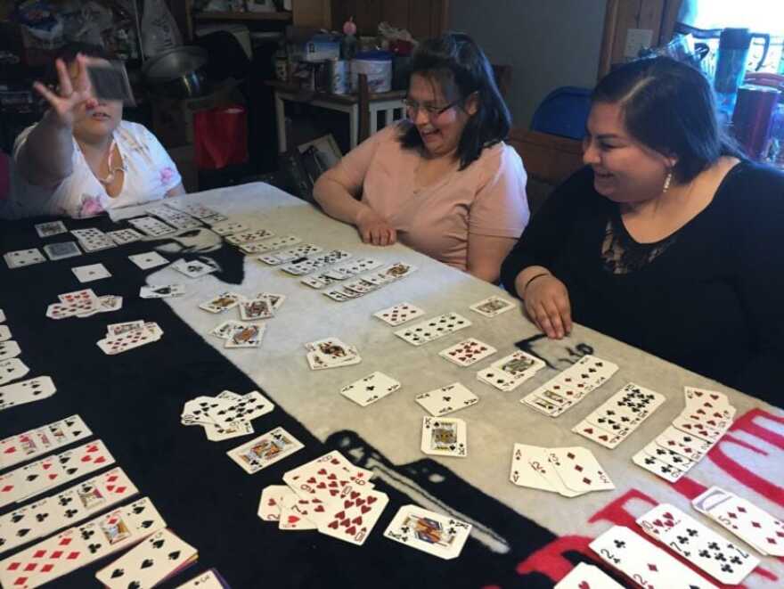 Christina Kanayurak (left) mid-discard during a game of snerts with her mother, Lilly Kanayurak, (center) and sister, Karen Hopson (right). April 17, 2019. (Photo by Ravenna Koenig/Alaska’s Energy Desk)