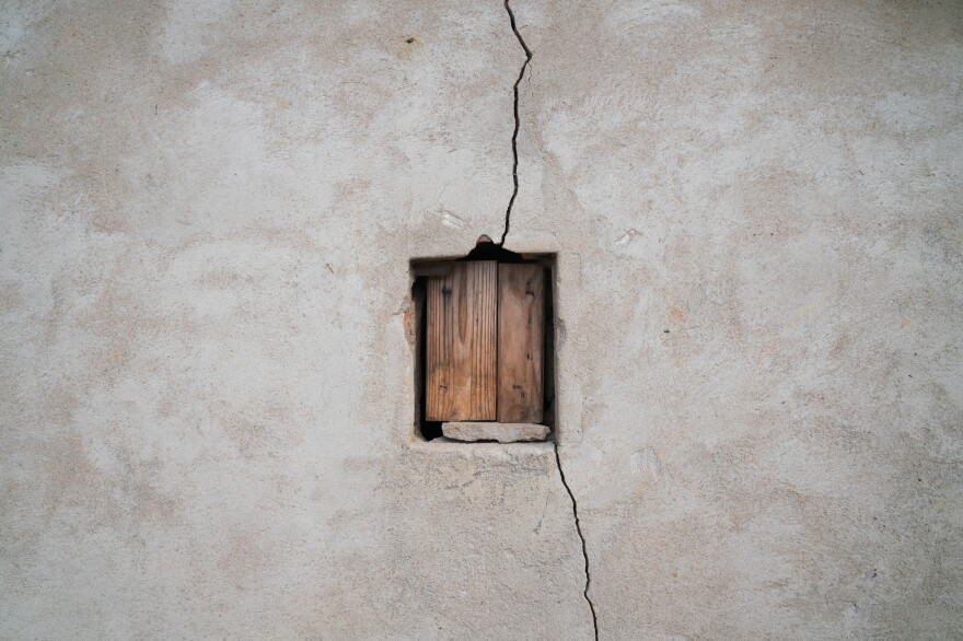 A small window on Machinga's shed is boarded up and a crack runs through the wall. Machinga has been rebuilding her house on her own, bit by bit, on the same spot, living among the same people who burned it down.