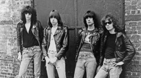 Black and white photo of four men in jeans and leather jackets
