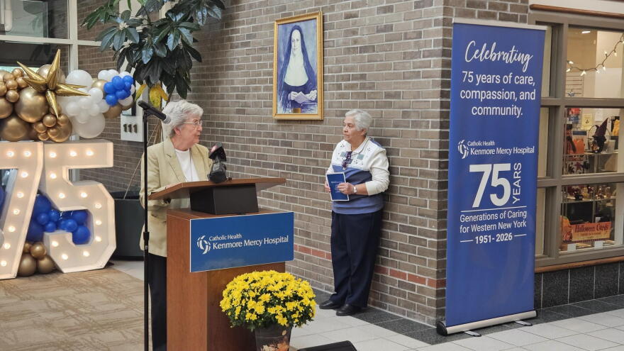 Sister Eileen O'Connor of the Sisters of Mercy, stands at a lectern leading a prayer at Kenmore Mercy Hospital.