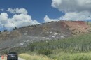 A burnt mountainside stands in the distance, cars line up on the road near it.