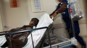 Wilfred Mobley pushes a patient to the radiology department at the University of Miami Hospital in Miami.
