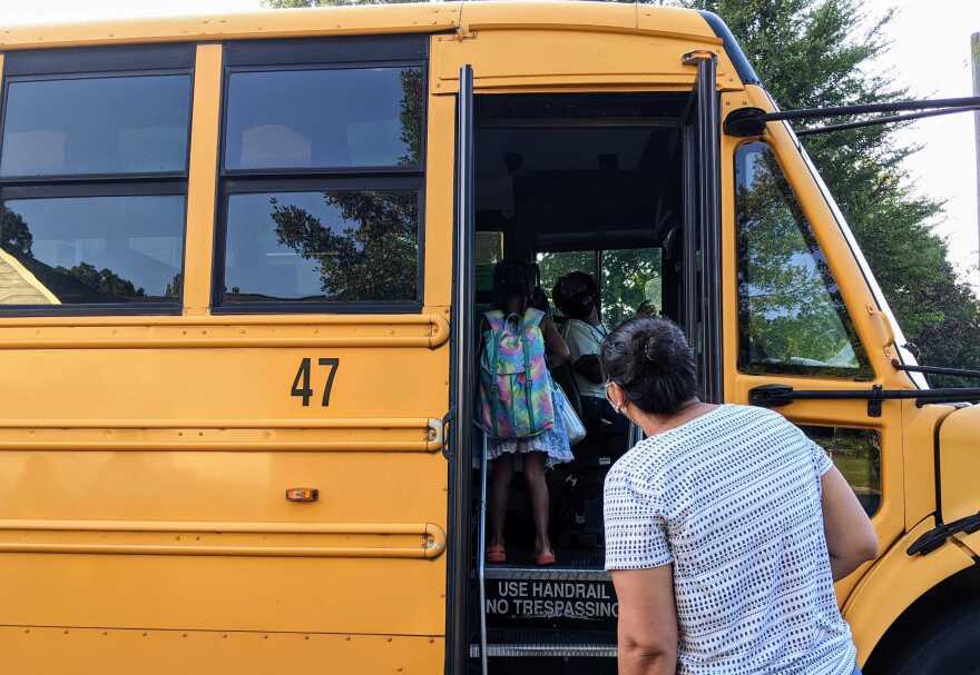 A mother drops her daughter off on a Durham Public Schools' bus. File photo.