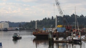 A crane sits on a barge in the bay. Local marine salvage and construction company Billeter Marine began the emergency operation Wednesday morning a the City Marina in Coos Bay.