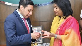 Secretary Diego Morales, left, holds a coin with an unnamed woman from India.