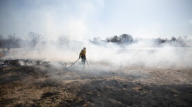 Bruce Villwock, district fire warden, hauls a hose used to wet down land adjacent to a controlled burn in Waterford in 2019.
