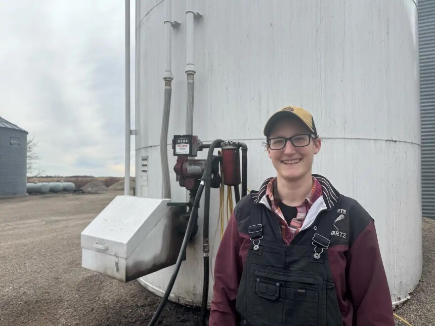 Megan Horsager poses in front of the gas pump on her farm in Montevideo, Minn., on April 8. She says the tank will run dry by June.