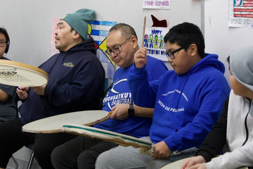 Three people drumming on hand drums.