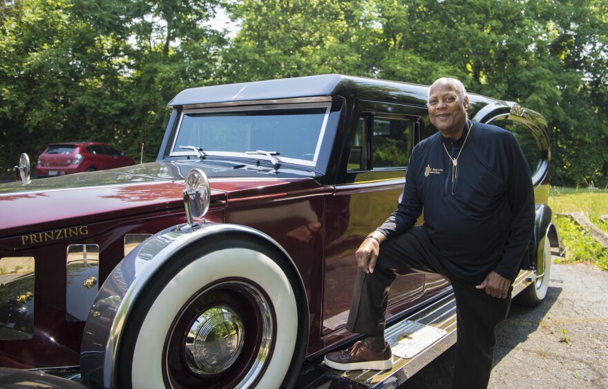 J.C. Battle III stands next to Chariot 1, a hearse designed to commemorate the first funerary vehicle his grandfather purchased after founding his funeral home in 1933.