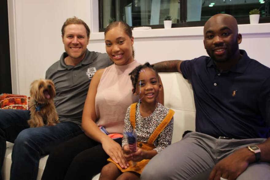 (Left to right) Co-Host Zach Giffin, Shanice Iniss, Kevin Iniss, and their daughter. Kevin and Shanice Iniss and their young daughter share a seat inside their new home which will be featured on Tiny House Nation. Photos by Jason Delgado for WMFE.