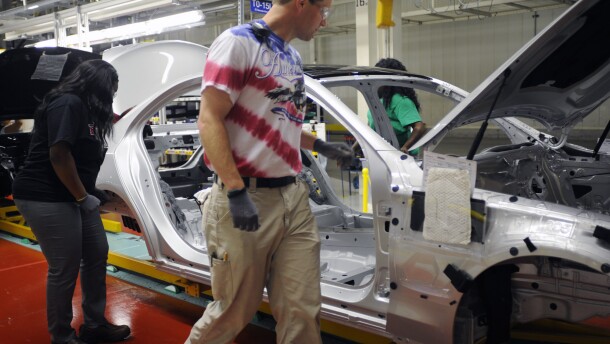 David Reeves, a group leader at the Mercedes-Benz factory in Vance, Ala., wears a red, white and blue T-shirt while inspecting a new sedan during the U.S.-Germany World Cup match on Thursday, June 26, 2014. Employees at the German-owned plant were encouraged to wear team colors to work to show their spirit. (AP Photo/Jay Reeves)