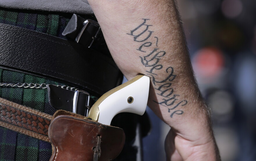 FILE - In this Jan. 26, 2015 file photo, a supporter of open carry gun laws, wears a pistol as he prepares for a rally in support of open carry gun laws at the Capitol, in Austin, Texas.  