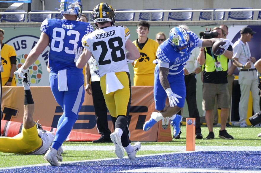 Kentucky running back Chris Rodriguez Jr. (24), right, scores on a 5-yard touchdown pass play as tight end Justin Rigg (83) and Iowa defensive back Jack Koerner (28) watch during the first half of the Citrus Bowl NCAA college football game, Saturday, Jan. 1, 2022, in Orlando, Fla. (AP Photo/Phelan M. Ebenhack)