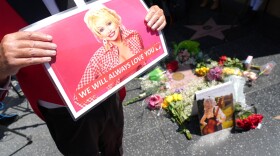 Actor Gregg Donovan holds a poster over Dolly Parton's star on the Hollywood Walk of Fame on Tuesday, Aug. 25, 2026, in Los Angeles. (AP Photo/Chris Pizzello)