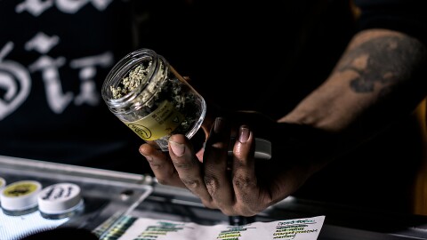A vendor showing off a jar of cannabis flowers.