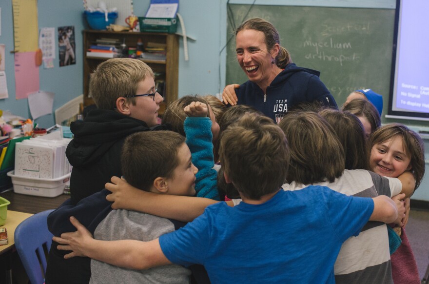 Susan Dunklee receives a group hug from third and fourth grade students after giving a presentation about biathlon at the Craftsbury Elementary School in Vermont.
